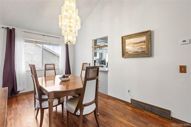 dining area with hardwood / wood-style flooring and a notable chandelier