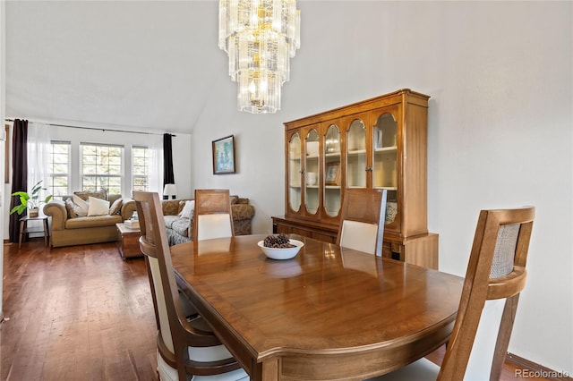 dining room with dark wood-type flooring, a chandelier, and vaulted ceiling