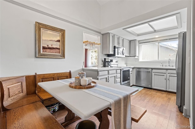 kitchen featuring sink, gray cabinetry, breakfast area, stainless steel appliances, and light wood-type flooring