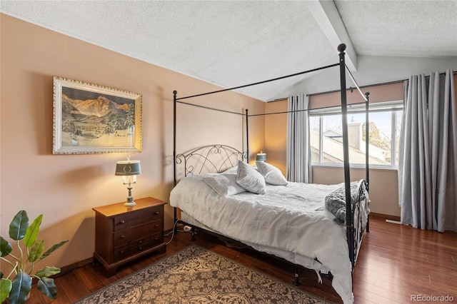 bedroom with dark hardwood / wood-style floors, a textured ceiling, and vaulted ceiling with beams