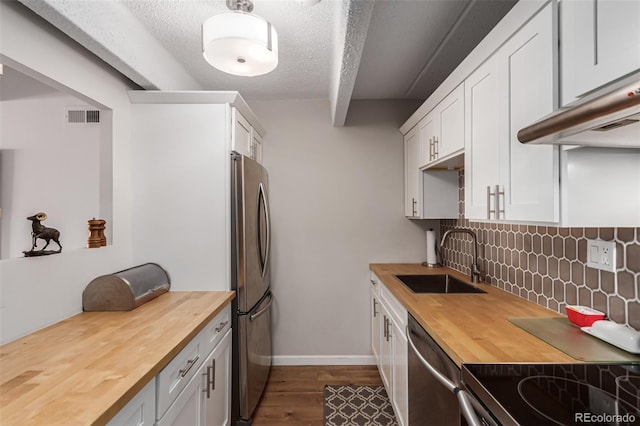 kitchen with butcher block counters, stainless steel appliances, backsplash, sink, and dark hardwood / wood-style flooring