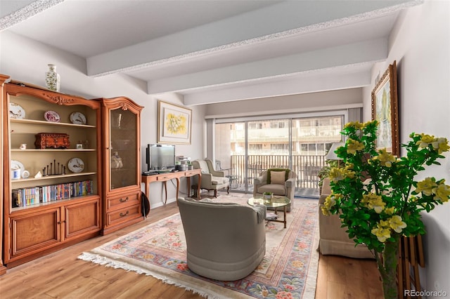 living room with beamed ceiling and light wood-type flooring