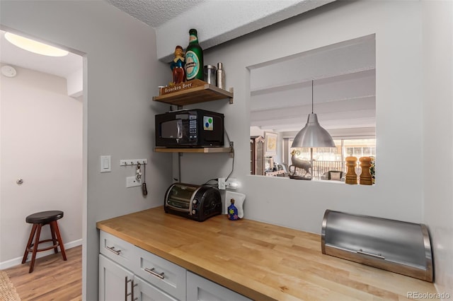 bar with white cabinets, a textured ceiling, light hardwood / wood-style flooring, pendant lighting, and wooden counters