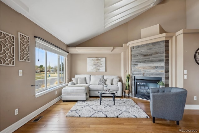 6595 Meade Ct, Arvada, CO 80003 - living area with lofted ceiling, a tiled fireplace, baseboards, and wood finished floors