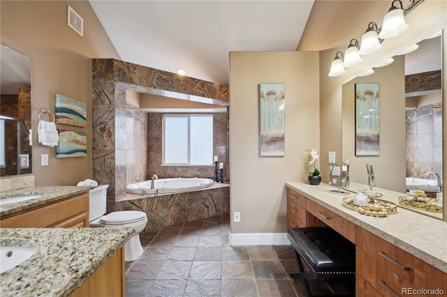 6595 Meade Ct, Arvada, CO 80003 - bathroom featuring stone tile floors, a bath, baseboards, and two vanities