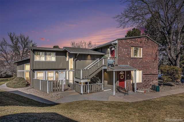 exterior space featuring board and batten siding, roof with shingles, and a yard