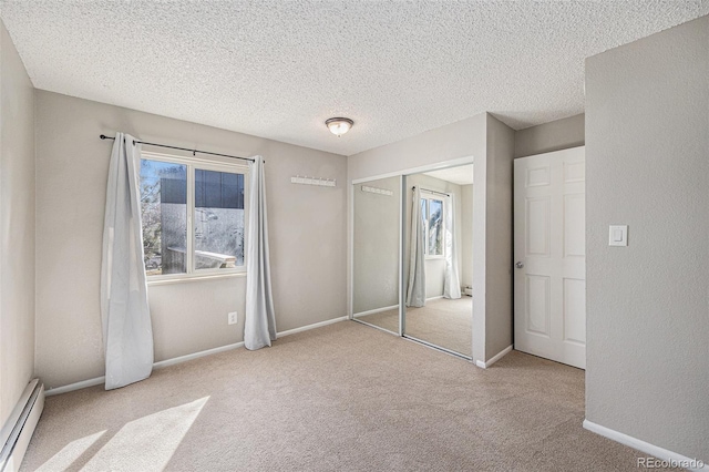 unfurnished bedroom featuring baseboards, a textured ceiling, carpet floors, a baseboard heating unit, and a closet