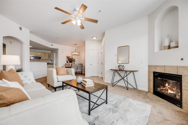 living room featuring light carpet, baseboards, visible vents, and a tiled fireplace