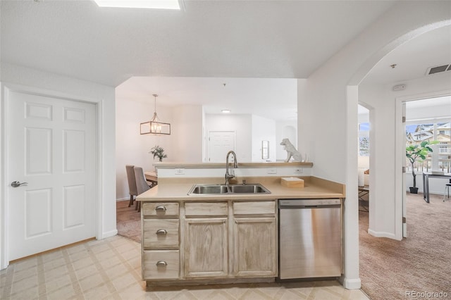 kitchen featuring visible vents, arched walkways, light countertops, stainless steel dishwasher, and a sink