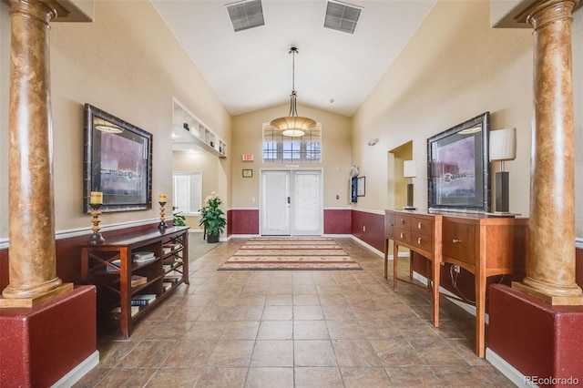 foyer featuring a wainscoted wall, visible vents, and decorative columns