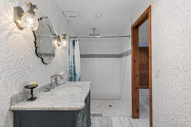 689 Red Deer Rd, Franktown, CO 80116 - bathroom featuring vanity, a tile shower, wood finished floors, and wallpapered walls