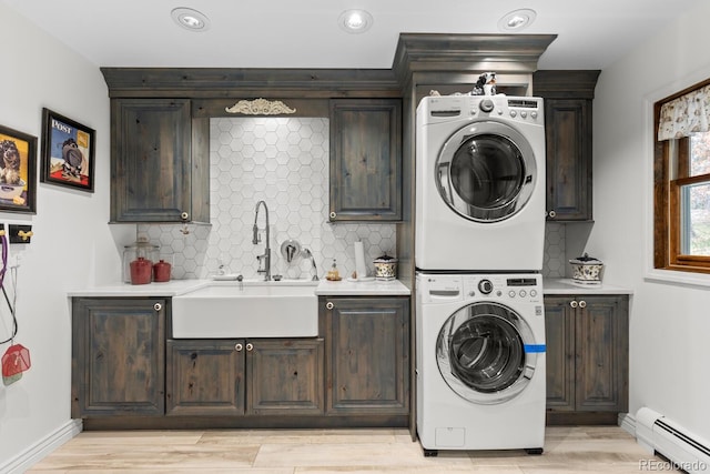689 Red Deer Rd, Franktown, CO 80116 - laundry area featuring baseboard heating, stacked washer / drying machine, cabinet space, light wood-style floors, and baseboards