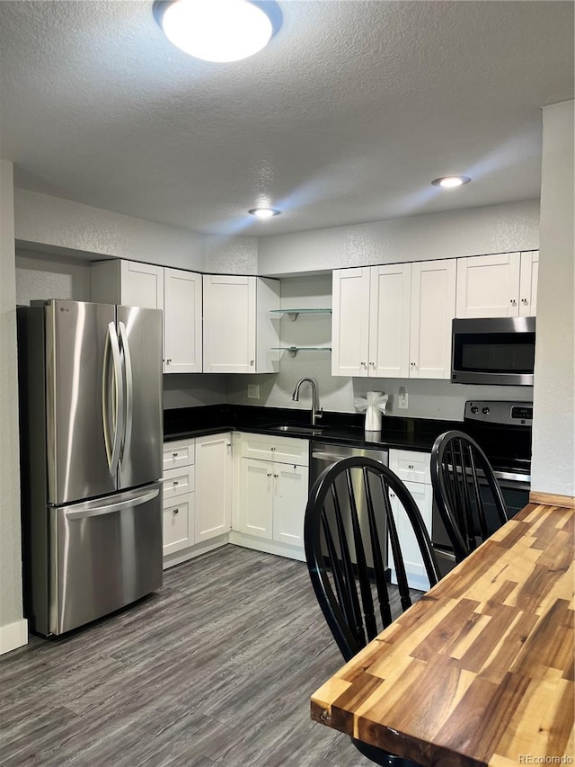 4899 S Dudley St Unit 1E, Littleton, CO 80123 - kitchen with appliances with stainless steel finishes, open shelves, white cabinetry, dark wood-style floors, and a textured ceiling