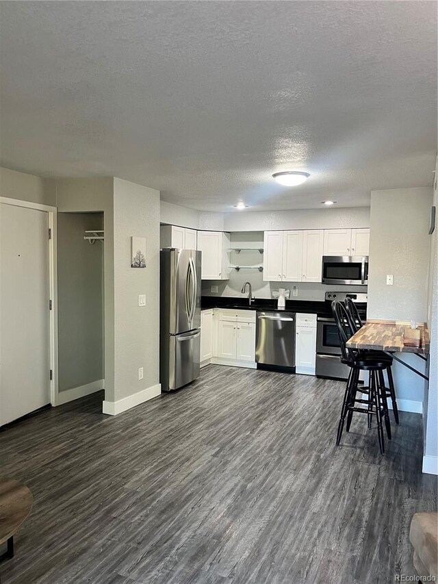 4899 S Dudley St Unit 1E, Littleton, CO 80123 - kitchen with stainless steel appliances, dark countertops, baseboards, dark wood finished floors, and a textured ceiling