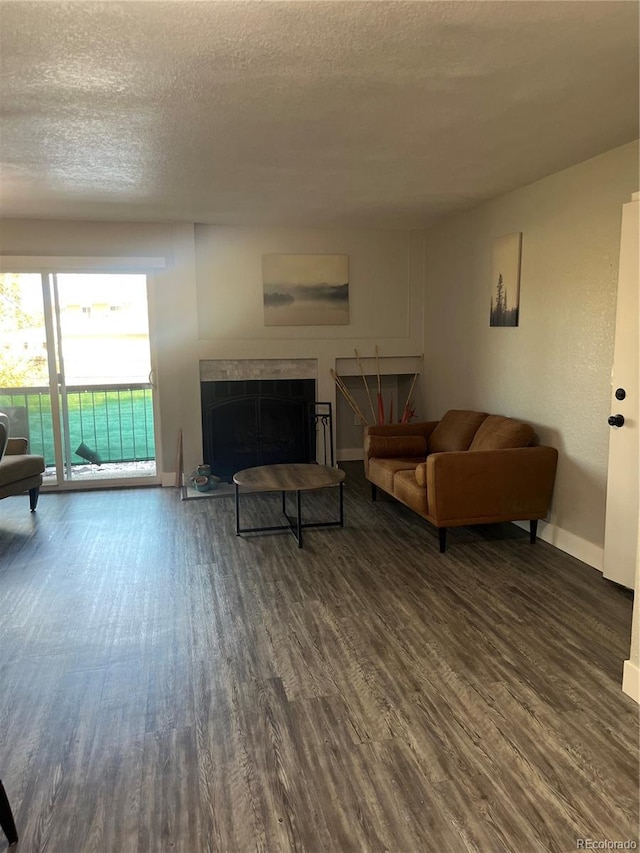 4899 S Dudley St Unit 1E, Littleton, CO 80123 - living area featuring dark wood-style flooring, baseboards, a textured ceiling, and a fireplace with raised hearth