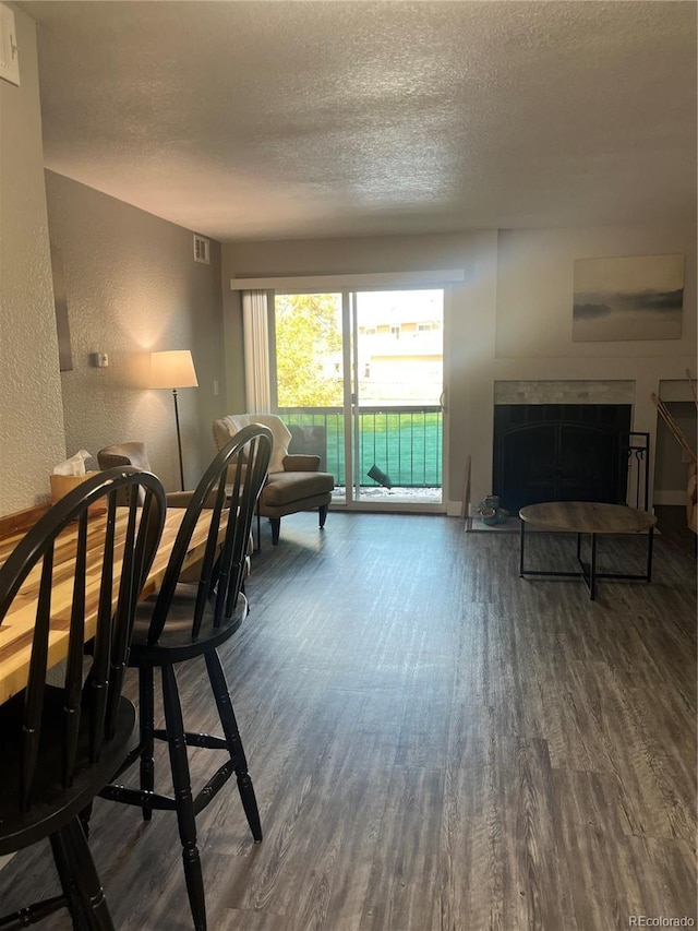 4899 S Dudley St Unit 1E, Littleton, CO 80123 - living room featuring wood finished floors, a textured ceiling, baseboards, a textured wall, and a fireplace with raised hearth