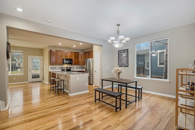 dining area with sink, light hardwood / wood-style flooring, and an inviting chandelier