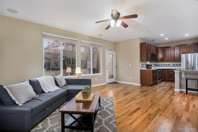 living room with ceiling fan and light hardwood / wood-style flooring