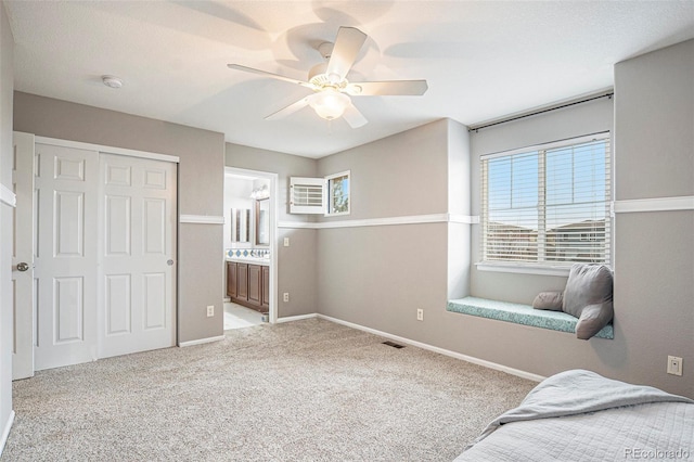 carpeted bedroom with ceiling fan, ensuite bathroom, and a closet