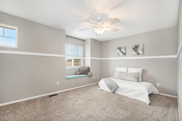 carpeted bedroom with a ceiling fan, baseboards, and visible vents