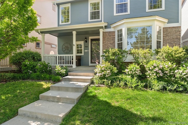 7860 E Ellsworth Ave, Denver, CO 80230 - view of front facade featuring covered porch, brick siding, and a front yard