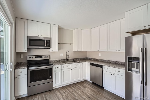 kitchen with sink, white cabinetry, hardwood / wood-style floors, stainless steel appliances, and a textured ceiling