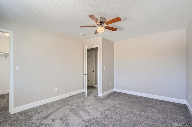 unfurnished bedroom with a spacious closet, a textured ceiling, carpet flooring, a closet, and ceiling fan