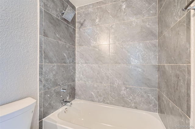 bathroom featuring tiled shower / bath and toilet