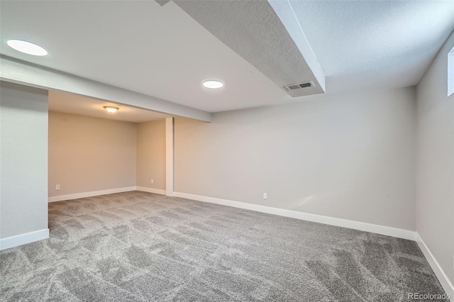 basement featuring light colored carpet and a textured ceiling