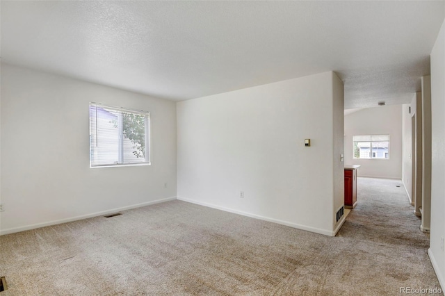 empty room with light carpet and a textured ceiling