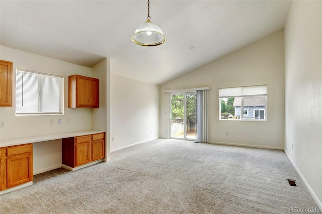 kitchen with pendant lighting, built in desk, vaulted ceiling, and light carpet