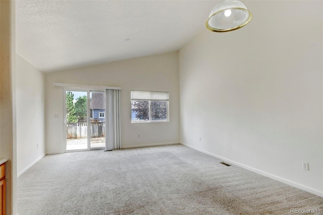 carpeted spare room with vaulted ceiling and a textured ceiling