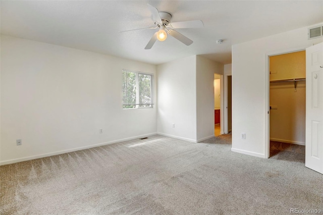 unfurnished bedroom with a spacious closet, a closet, ceiling fan, and carpet flooring