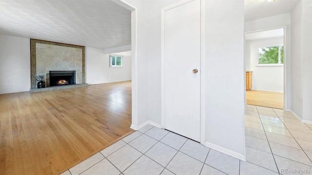 interior space featuring light hardwood / wood-style floors, a textured ceiling, and a tile fireplace