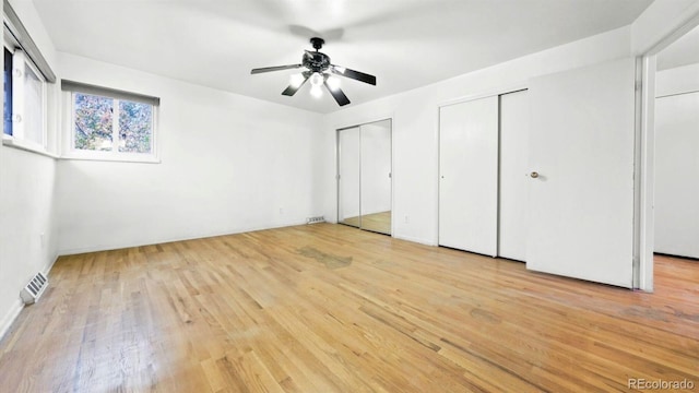 unfurnished bedroom with light hardwood / wood-style flooring, two closets, and ceiling fan