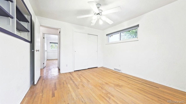 unfurnished bedroom featuring light hardwood / wood-style flooring, multiple windows, a closet, and ceiling fan