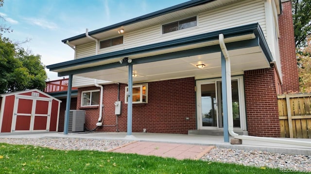 back of property with a storage shed, cooling unit, and a patio