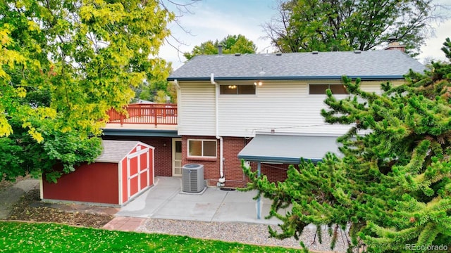 rear view of property with central air condition unit, a patio, and an outbuilding