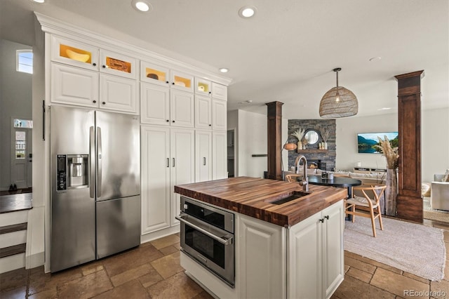 854 Countrybriar Ln, Highlands Ranch, CO 80129 - kitchen featuring butcher block counters, appliances with stainless steel finishes, stone tile floors, open floor plan, and decorative columns
