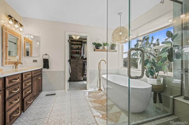 854 Countrybriar Ln, Highlands Ranch, CO 80129 - bathroom with tile walls, vanity, a walk in closet, a freestanding tub, and a wainscoted wall