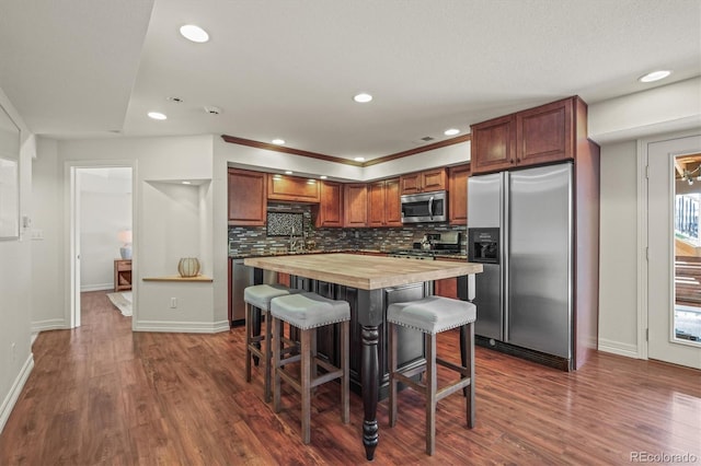 854 Countrybriar Ln, Highlands Ranch, CO 80129 - kitchen with appliances with stainless steel finishes, wood counters, a breakfast bar area, recessed lighting, and dark wood-style floors
