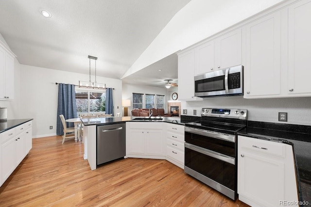 2730 River View Dr, Broomfield, CO 80023 - kitchen featuring stainless steel appliances, dark countertops, a peninsula, light wood-style floors, and lofted ceiling
