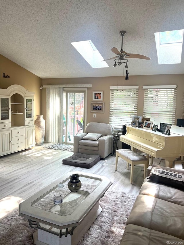 living room with lofted ceiling with skylight, a ceiling fan, a textured ceiling, and wood finished floors