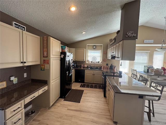 kitchen with a kitchen breakfast bar, a peninsula, vaulted ceiling, black appliances, and a sink