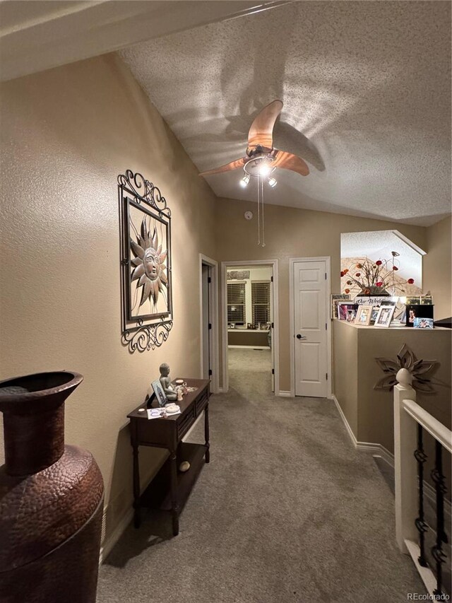 hallway with lofted ceiling, carpet flooring, a textured ceiling, and an upstairs landing