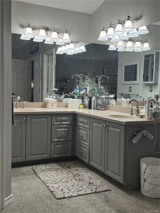 full bathroom with a sink, a textured ceiling, and double vanity