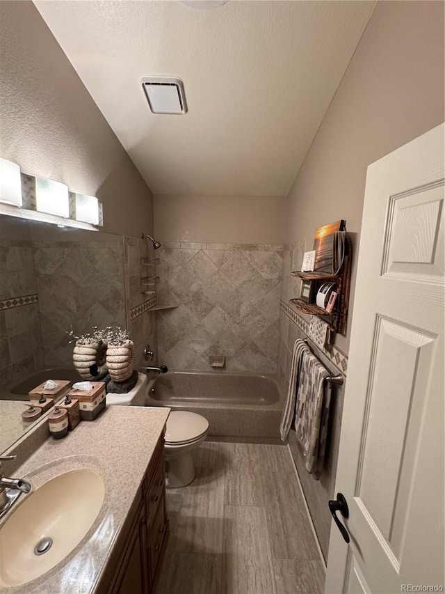 bathroom with lofted ceiling, shower / bath combination, toilet, vanity, and wood finished floors