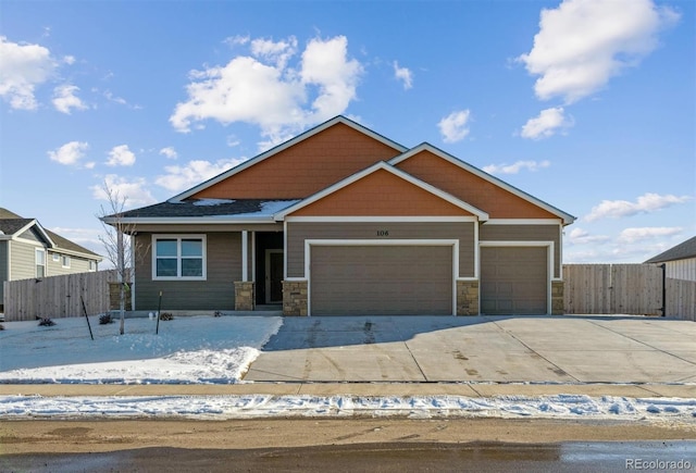 craftsman-style house featuring a garage, stone siding, fence, and concrete driveway