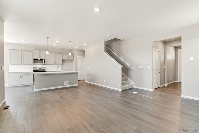 unfurnished living room with light hardwood / wood-style flooring and sink