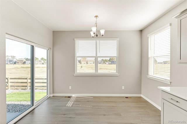 unfurnished room with light hardwood / wood-style flooring and a chandelier